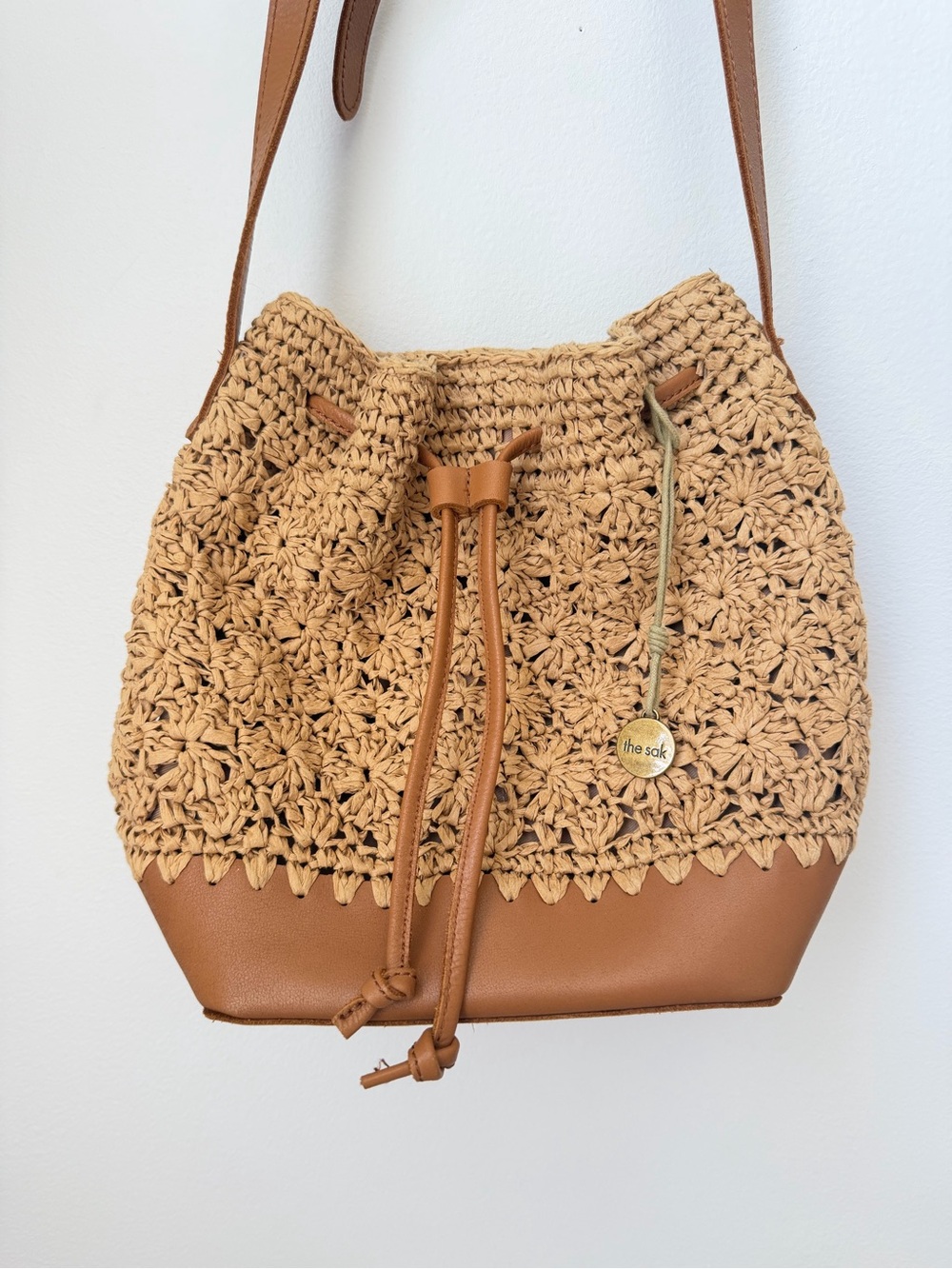 The Sak Raffia Straw Bucket Bag with Leather Bottom and Adjustable Strap